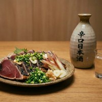 かつおの藁焼きタタキと辛口の日本酒が並んでいる様子